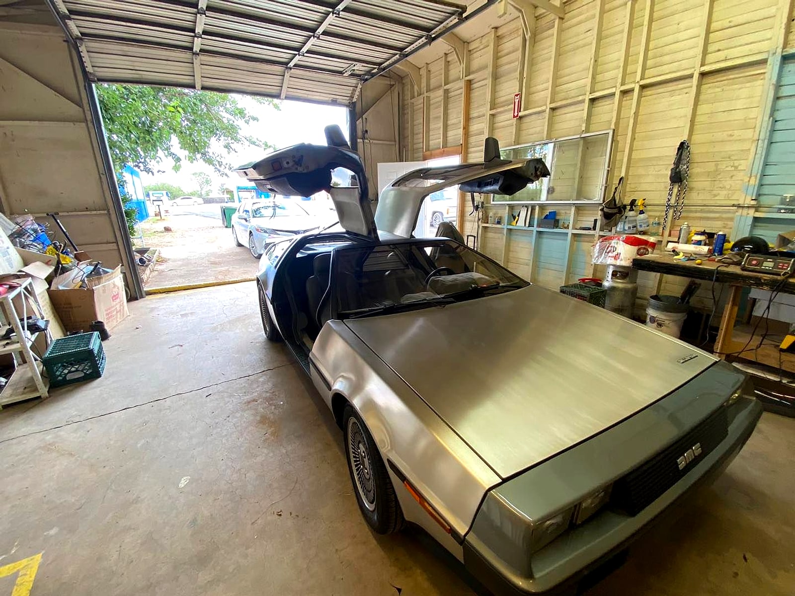 DeLorean with its gull-wing doors open in the detailing bay